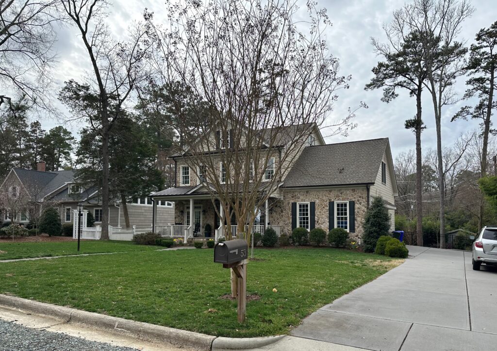 Photo of a large house on a lot with a lawn and one tree