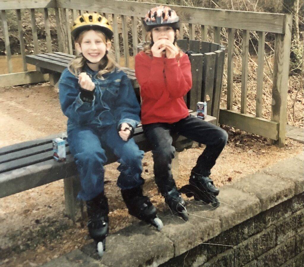 Two children sitting on a bench in skates