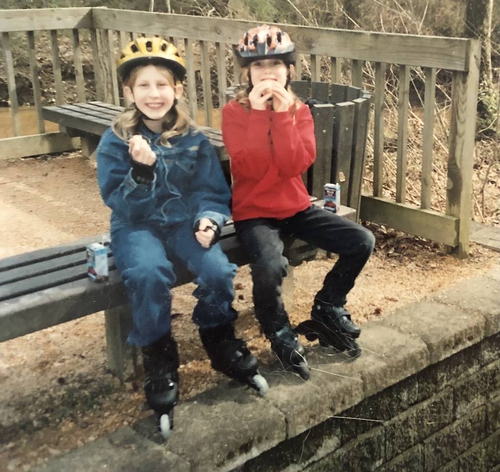 Two children sitting on a bench in skates