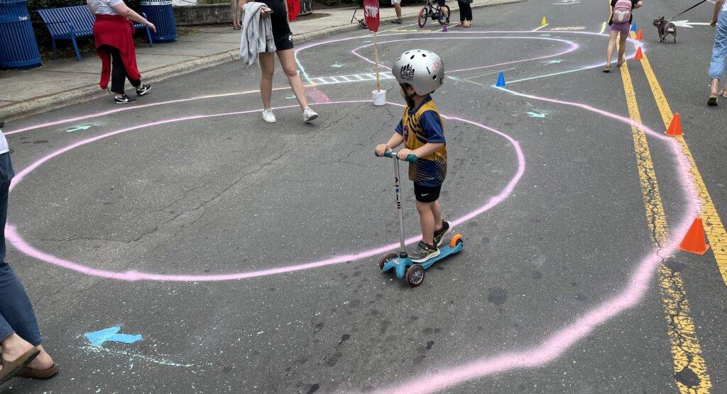 A child on a scooter enjoys a traffic garden