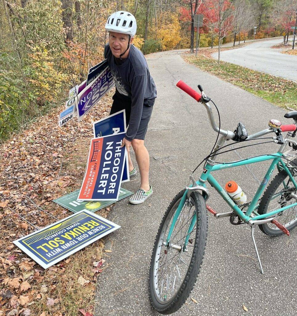 A cyclist collecting campaign signs by bike