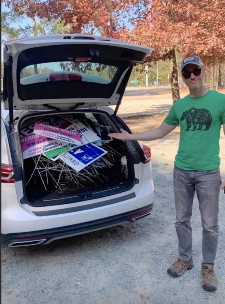 Jon Mitchell stand at the boot of a car full of campaign signs