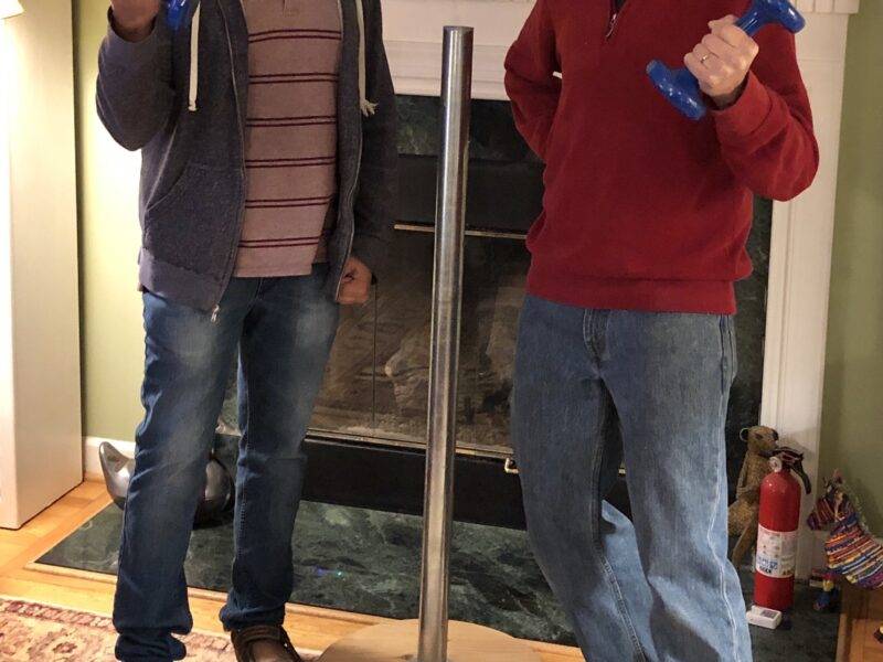 Two people practicing feats of strength next to a Festivus pole