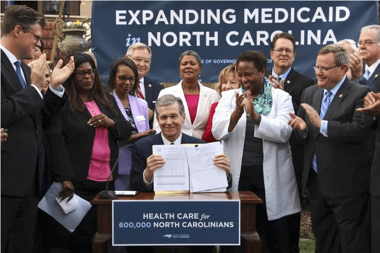 governor cooper signing the bill to expand medicaid