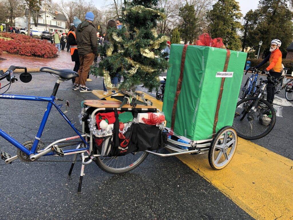 A bike towing a trailer with a giant gift on it