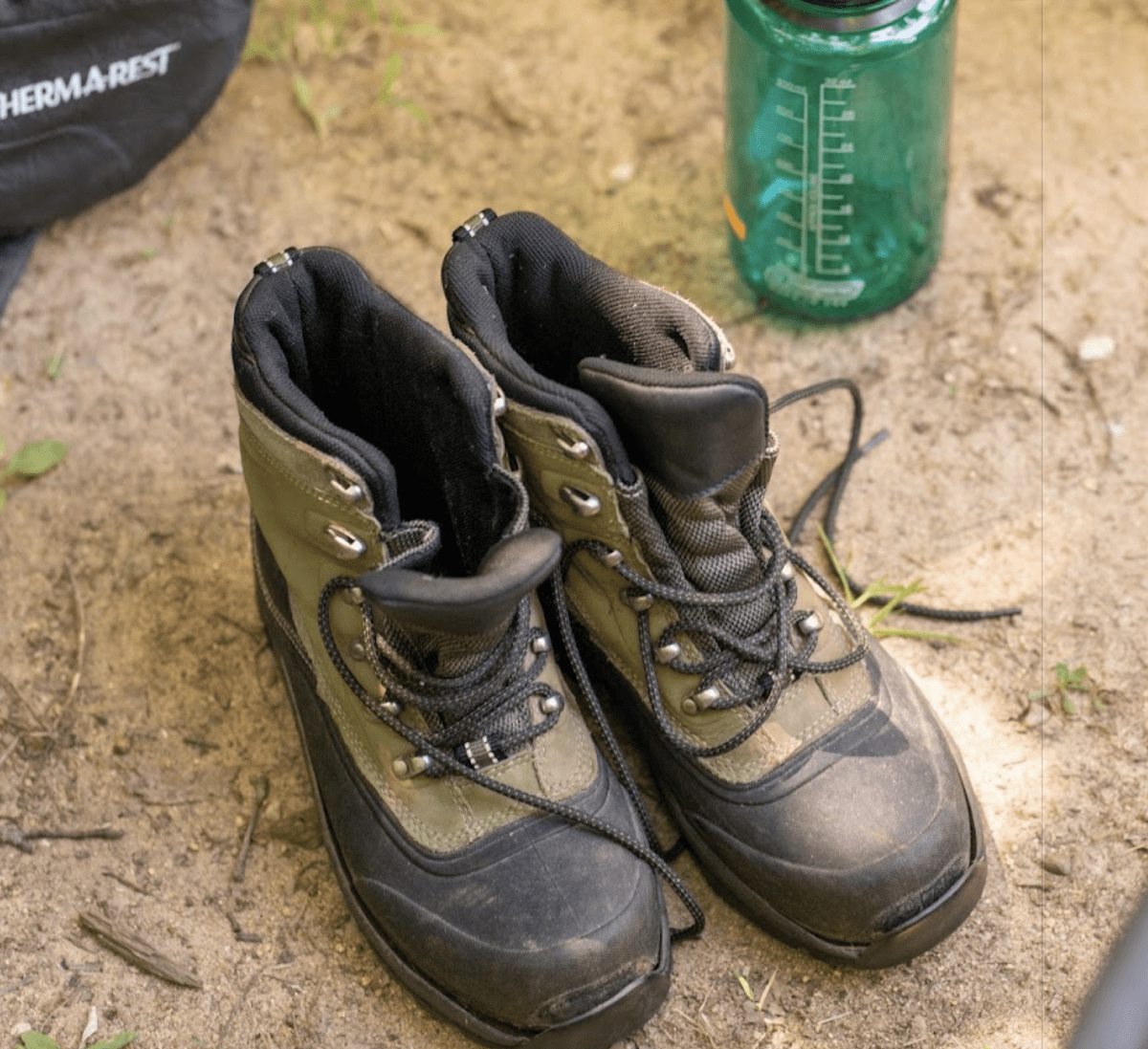 A pair of hiking boots next to a Nalgene water bottle