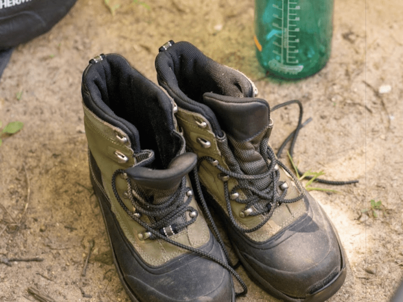 A pair of hiking boots next to a Nalgene water bottle