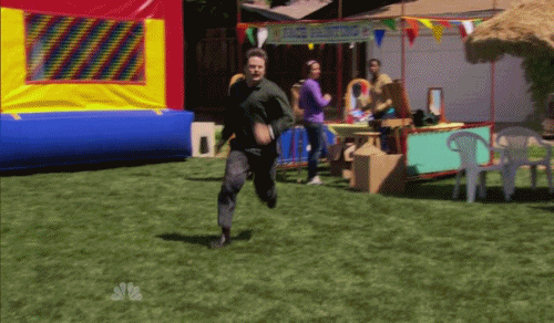 A man running at a festival and slipping on the grass. The man appears uninjured