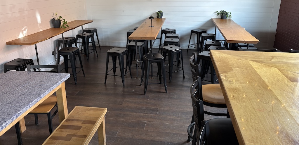 Some bar tables and stools in front of a cinderblock wall