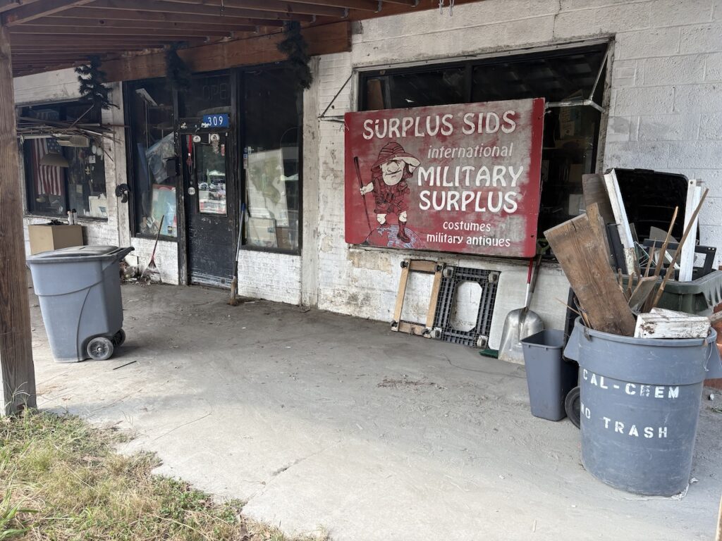 The porch of sids with a red sign and garbage cans