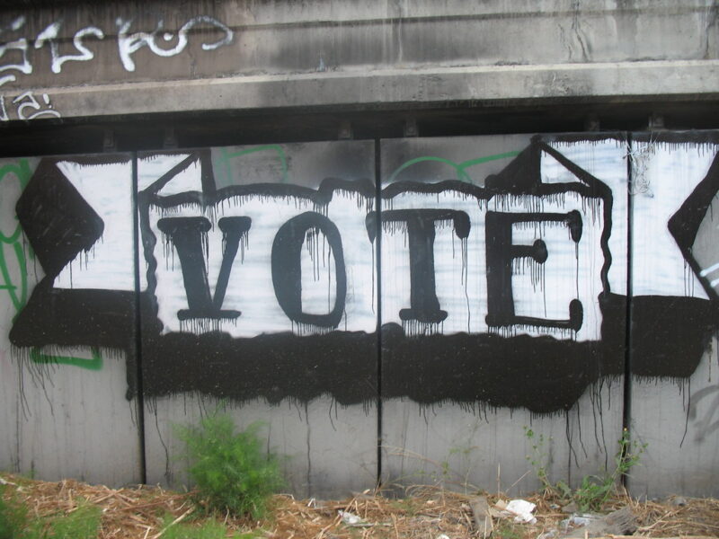 The word 'vote' spray painted on a concrete wall