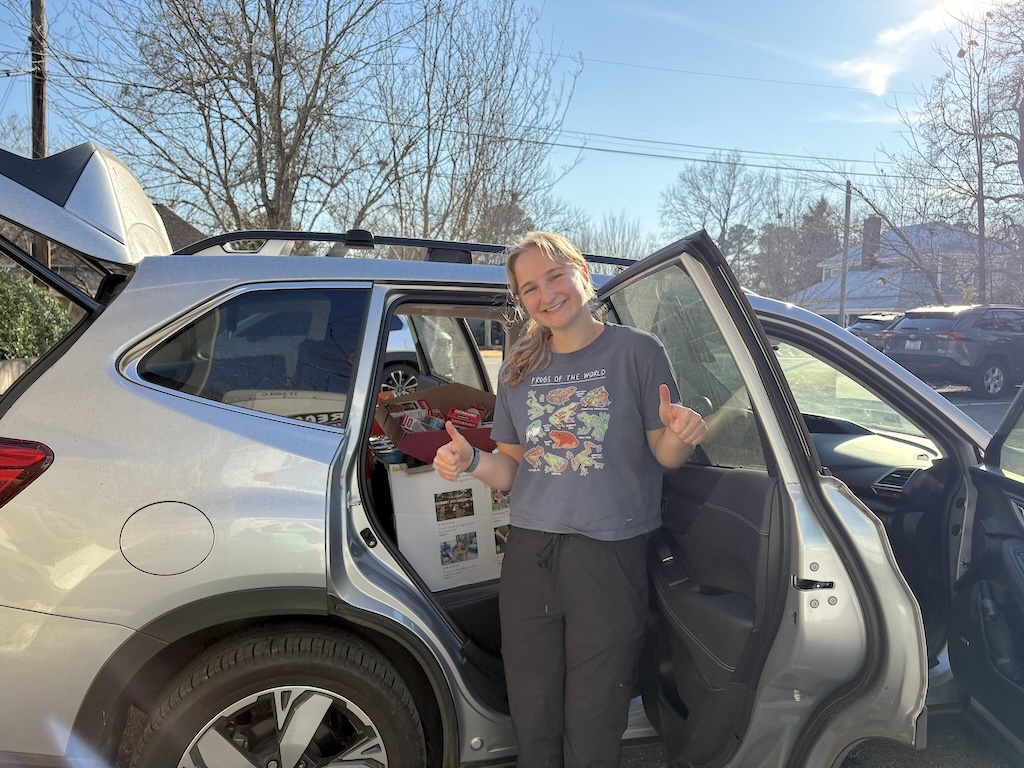 A representative from CJ’s Pantry–a food pantry benefitting students and staff at the UNC Chapel Hill Gillings School of Global Public Health–poses with donations from PORCH received as part of PORCH’s Food for Pantries program.