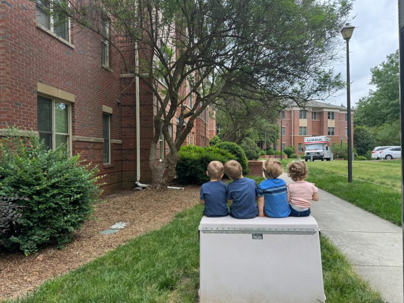 Four children sit outside Baity Baity Hill, an on-campus UNC-Chapel Hill apartment community